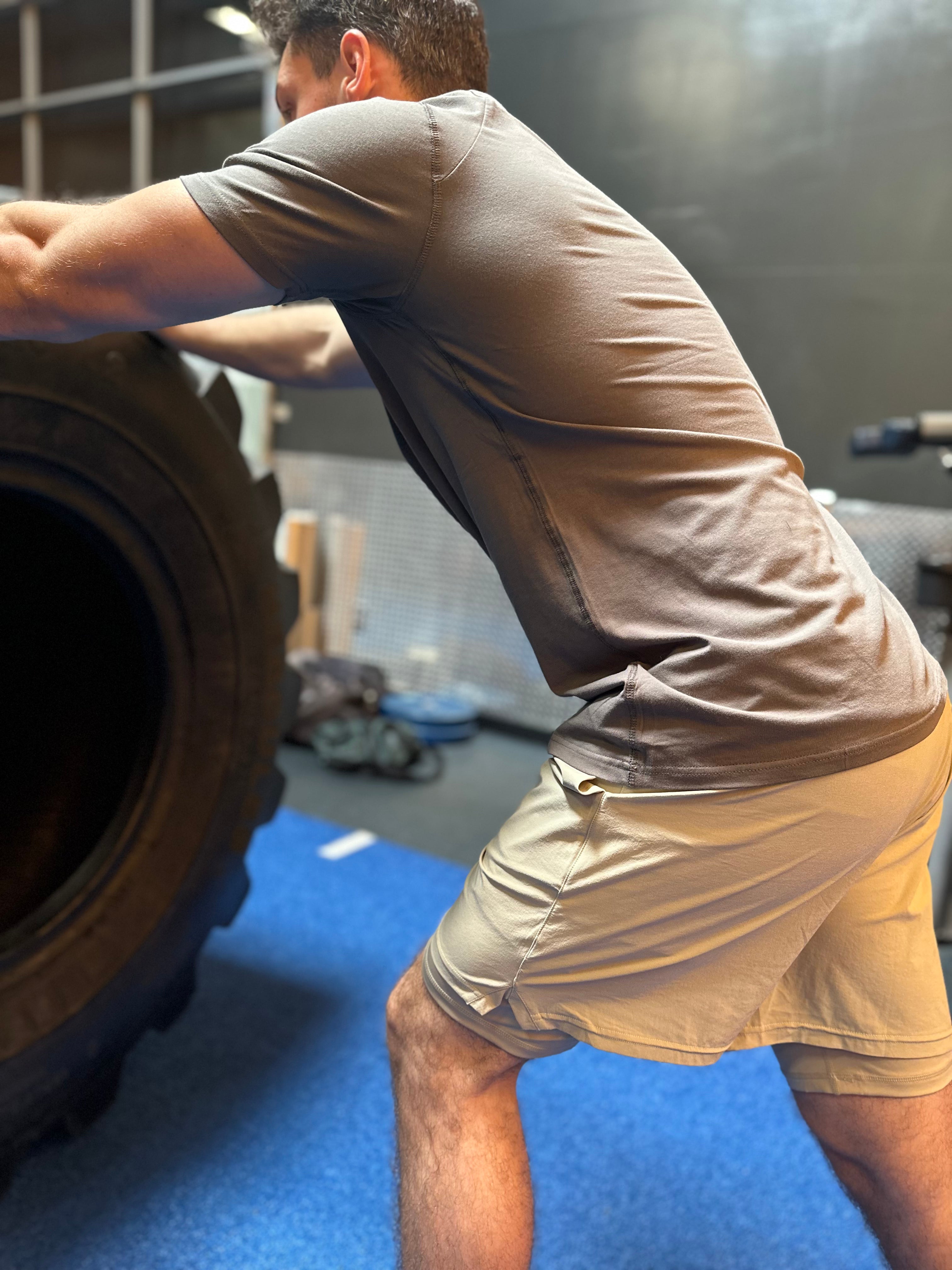 A man pushing a large tire in a gym, demonstrating strength and determination in his workout routine.