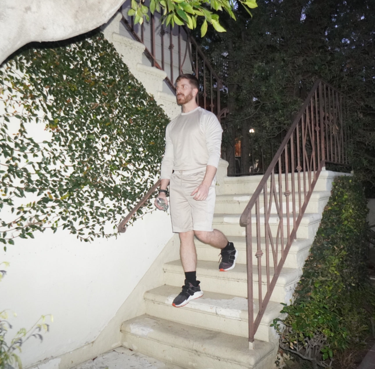 A man in a white shirt and shorts climbing down stairs confidently.